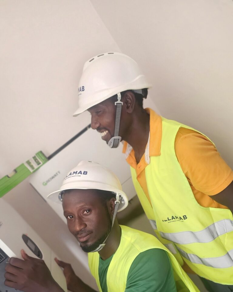 Two Illamab Energy Solutions technicians inspecting inverter and energy storage equipment on site